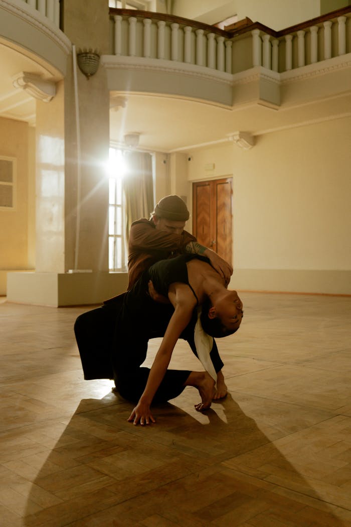 Home Elegant contemporary dance duo performing a dynamic pose in warm-lit interior space.
