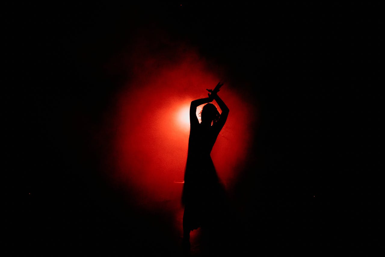 Home Captivating silhouette of a dancer performing gracefully with a dramatic red background.